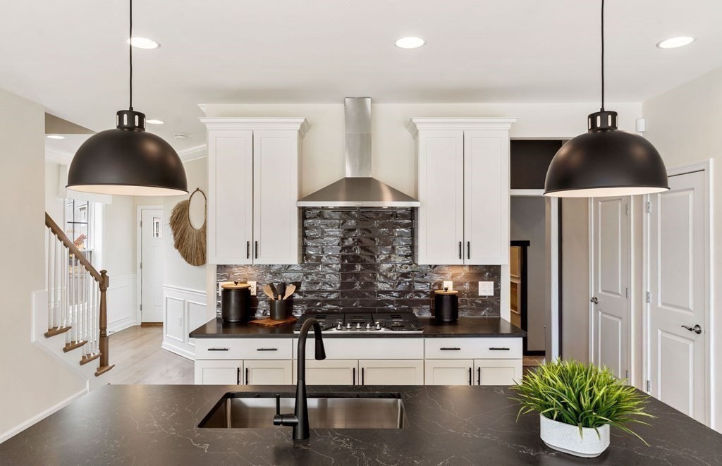 a kitchen with stainless steel appliances kitchen island granite countertop a sink a stove and a wooden floor