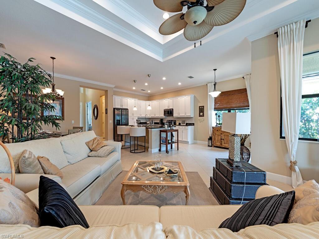 a living room with furniture kitchen view and a chandelier