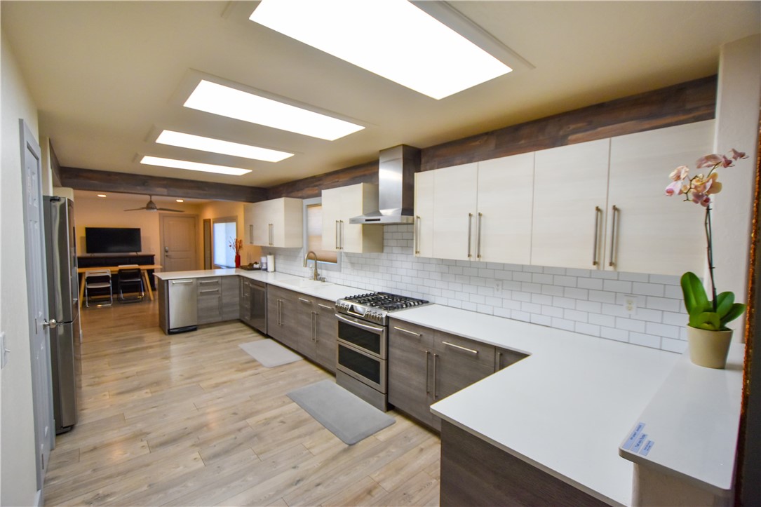 a large kitchen with a large counter top space a sink and stainless steel appliances