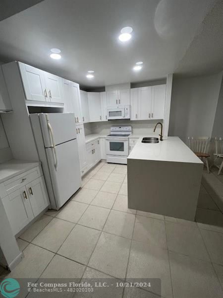 a kitchen with a sink a refrigerator and white cabinets