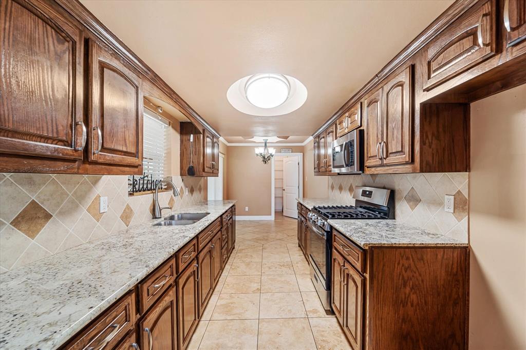 a kitchen with stainless steel appliances granite countertop a sink a stove and cabinets