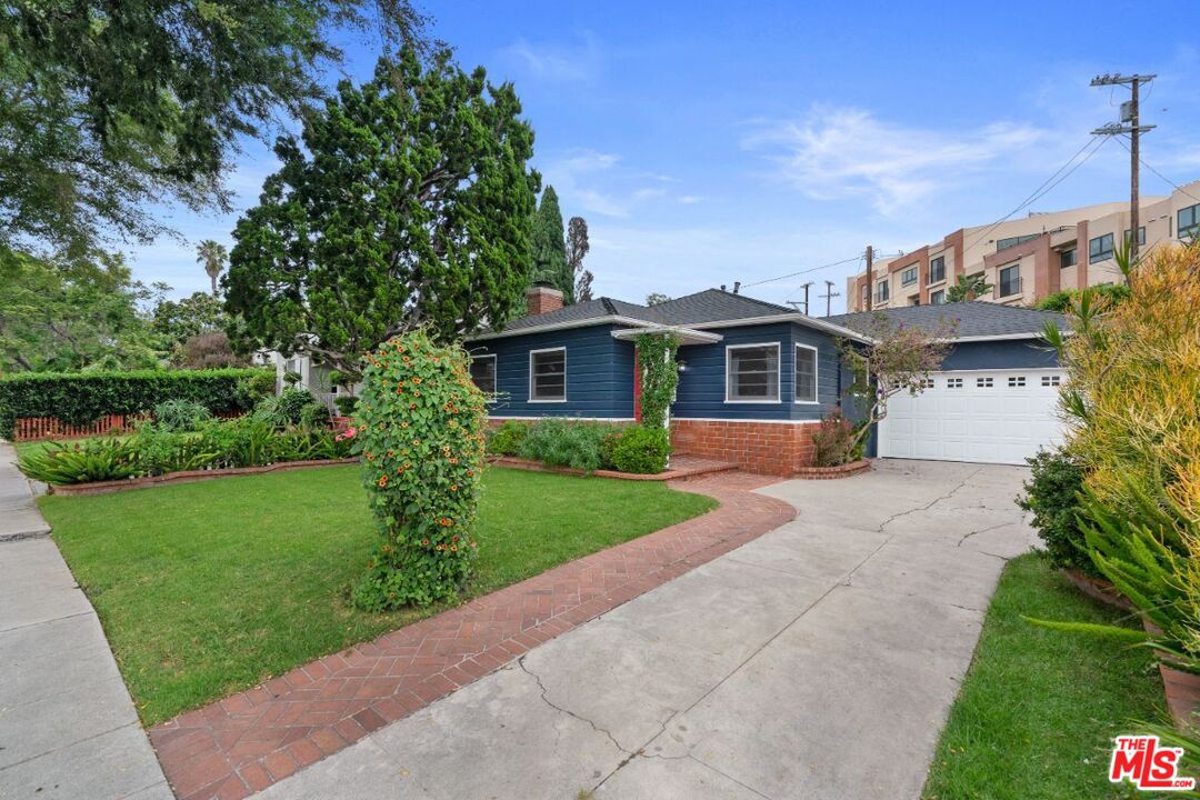 a front view of a house with a yard and potted plants