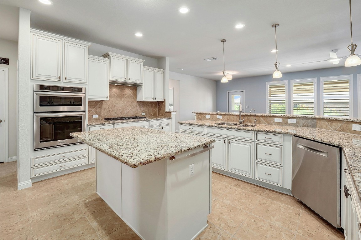 Gorgeous kitchen with conveniently located sink looking out over the the granite counters to the living, informal dining area.  Island and added cupboards add to work space, note the accent lighting above the counter.