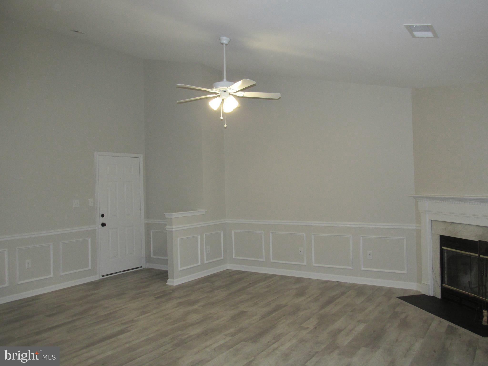 an empty room with wooden floor fan and window