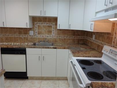 a kitchen with granite countertop white cabinets and white appliances