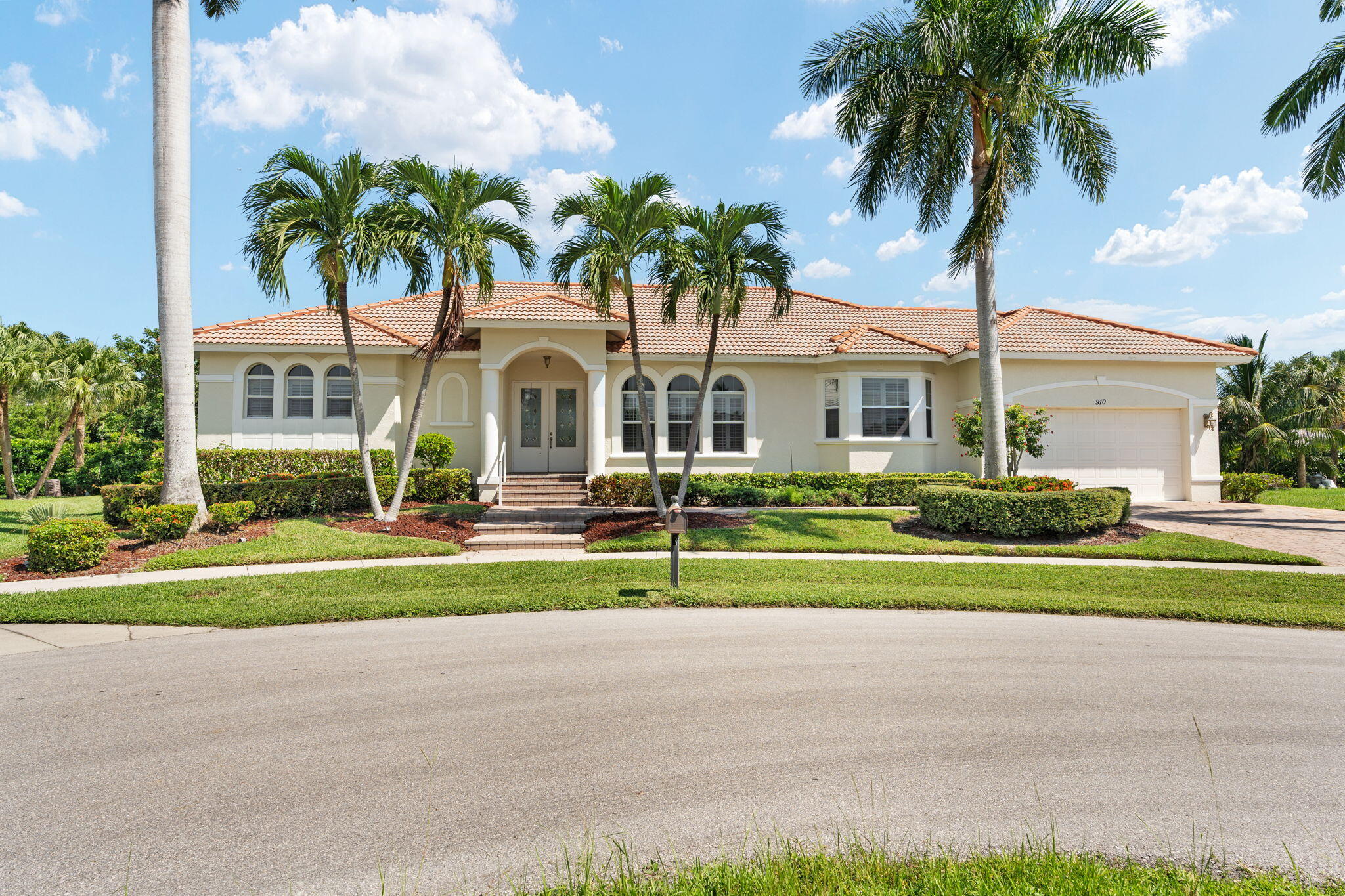 a front view of a house with a garden and trees