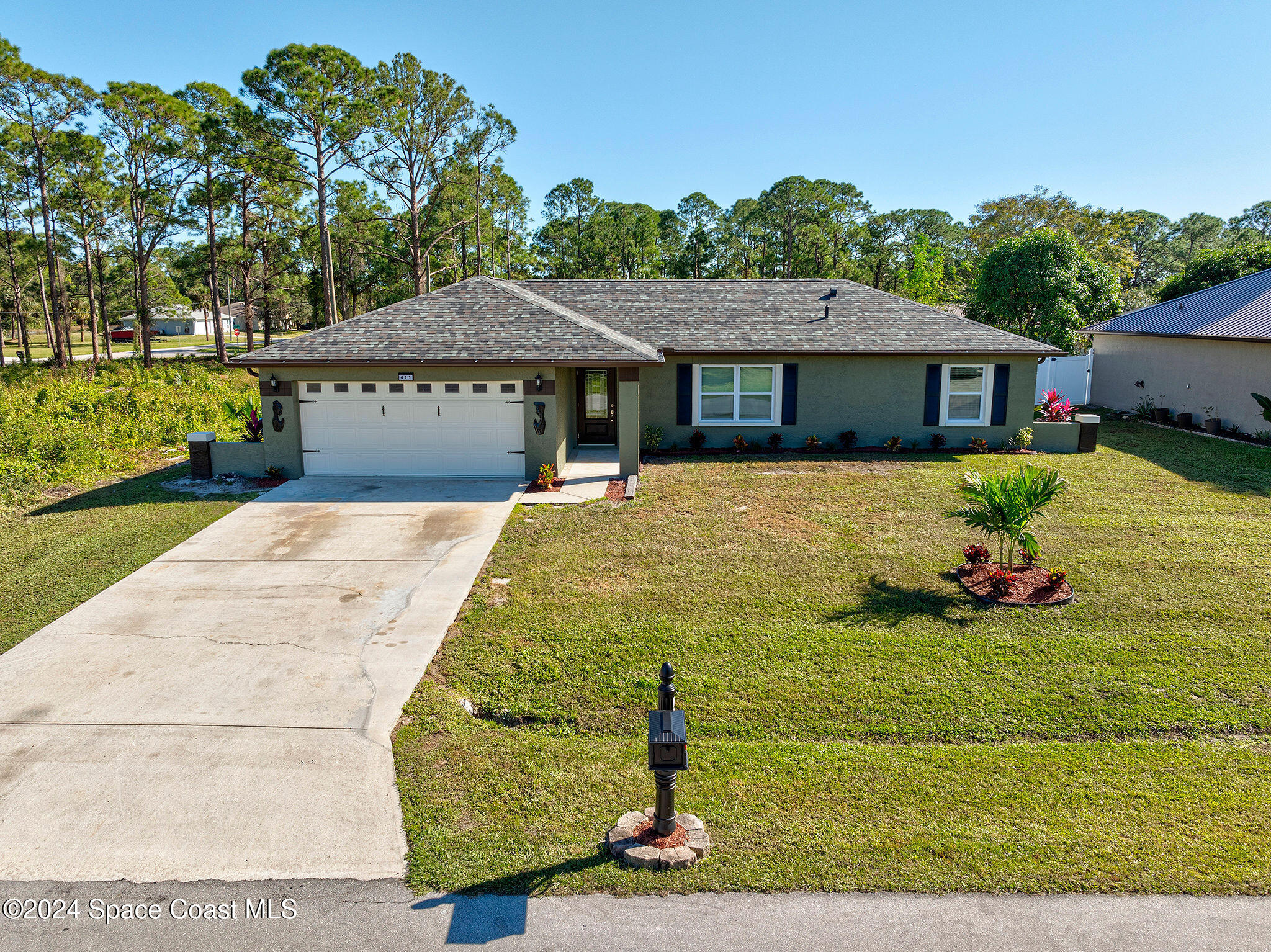 a front view of house with yard and trees in the background