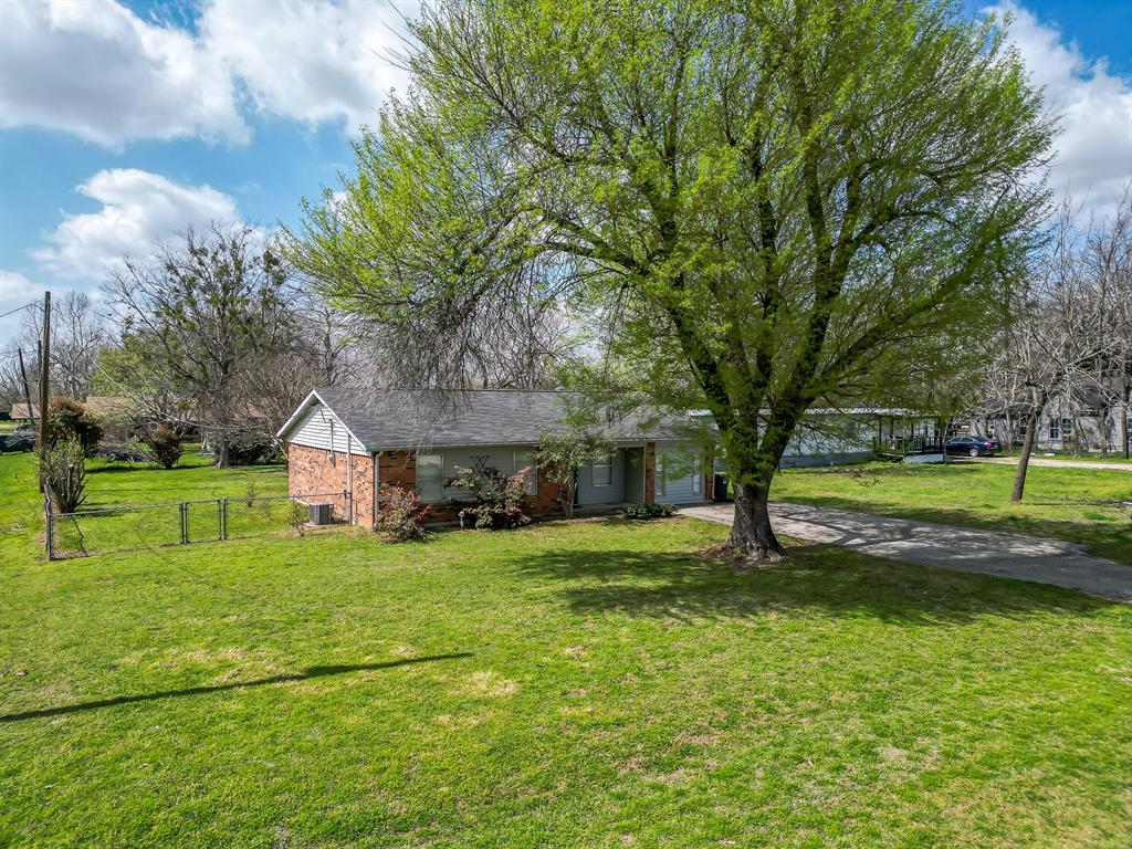 a view of a house with a big yard and large trees