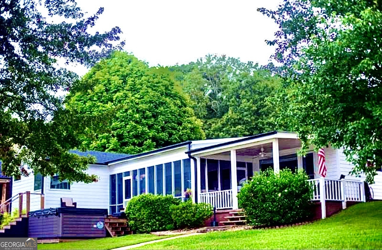 a view of a yard in front of a house with plants and large tree