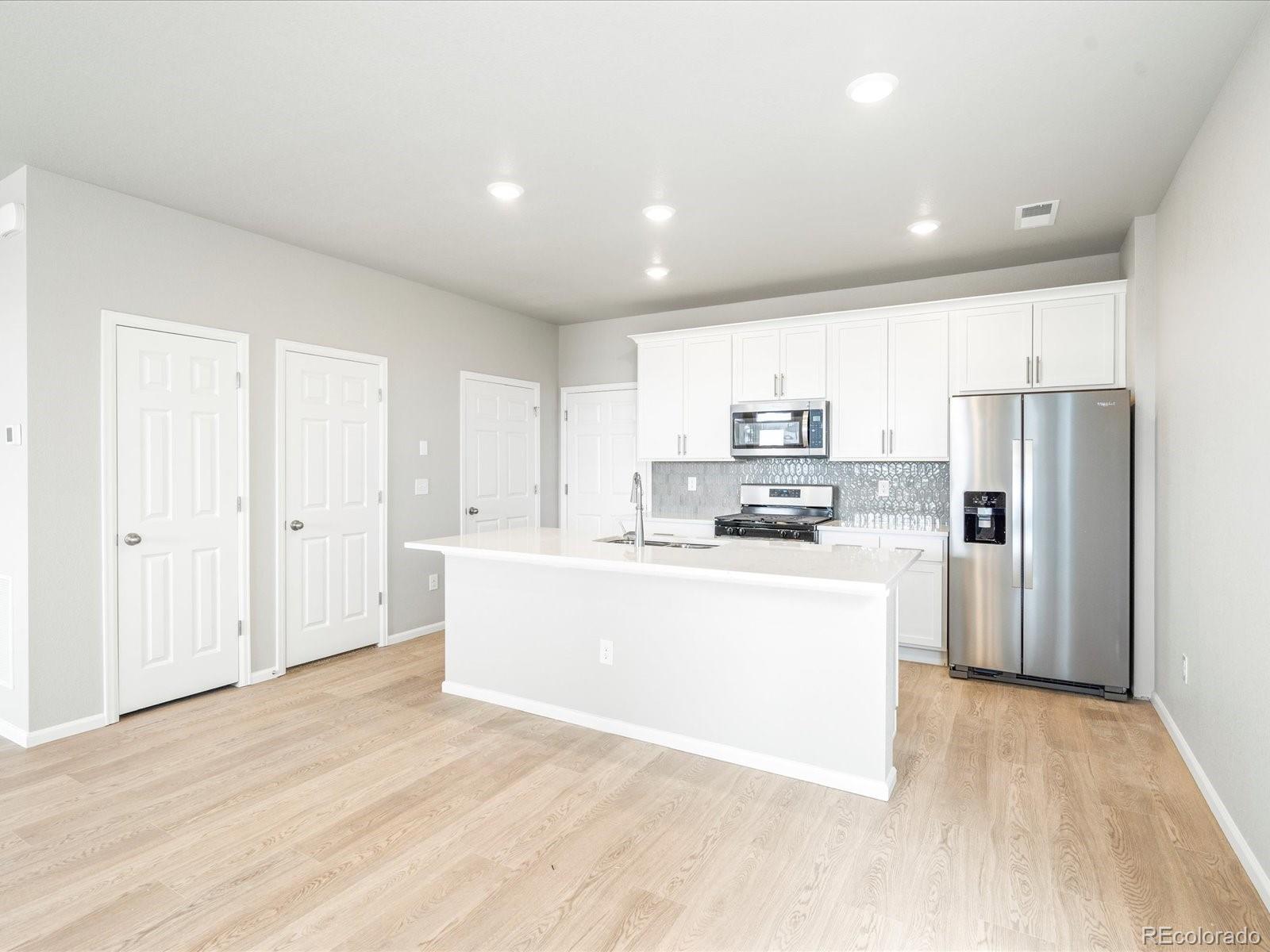 a view of kitchen with stainless steel appliances refrigerator stove microwave and cabinets