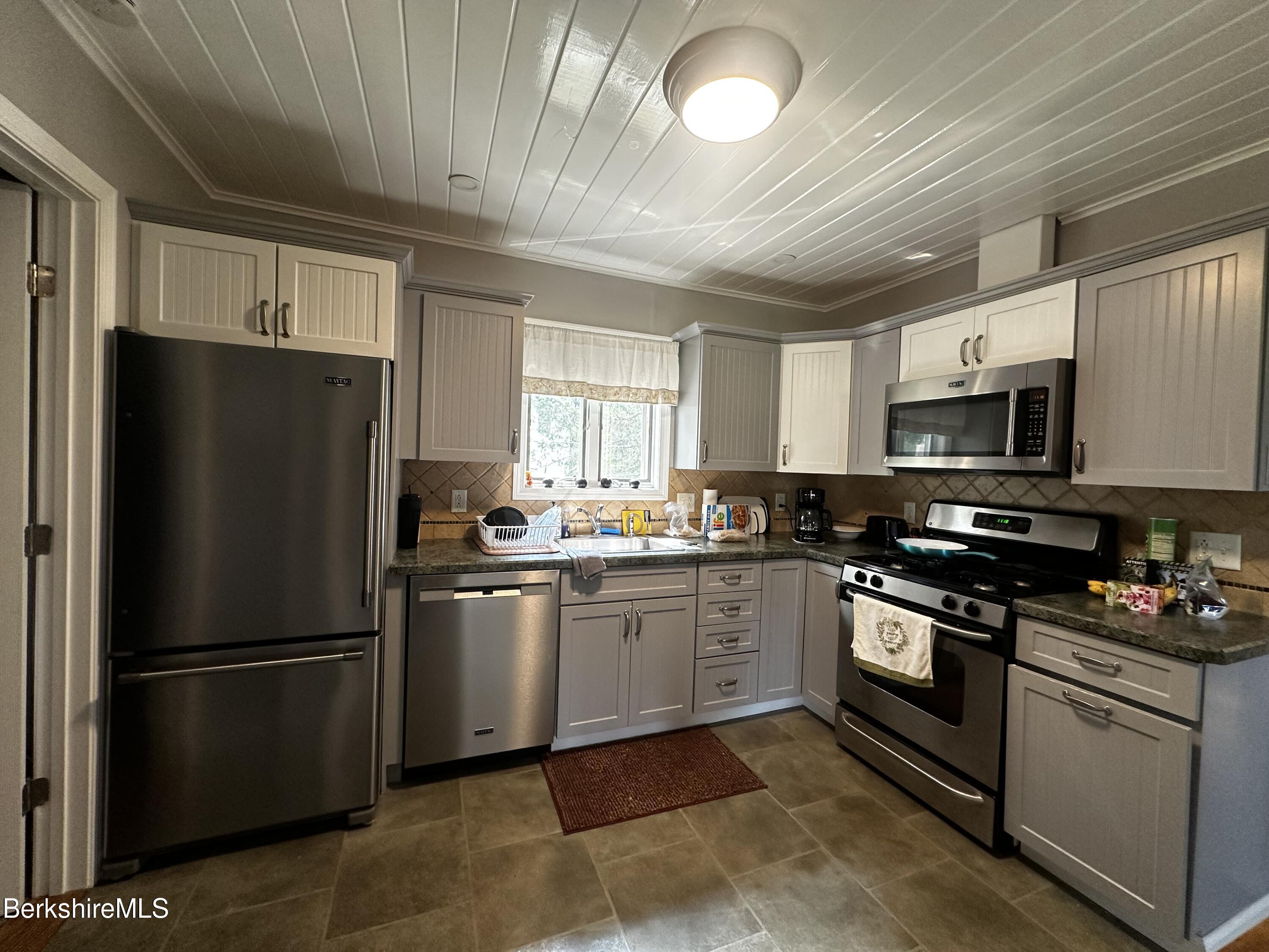 a kitchen with stainless steel appliances granite countertop a refrigerator stove a sink dishwasher and microwave