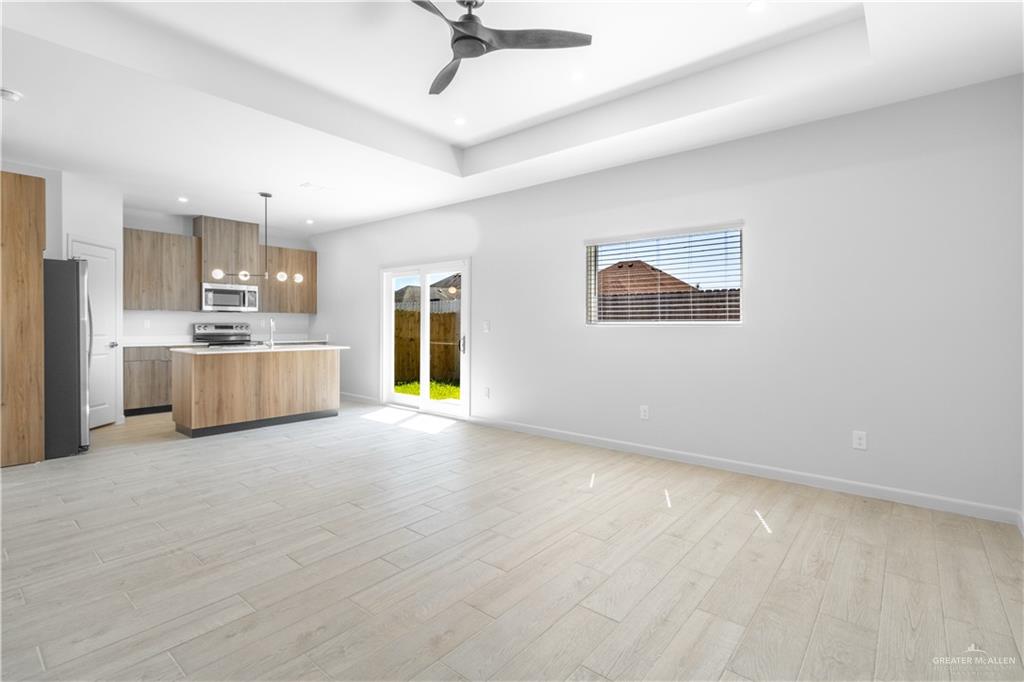 a view of a kitchen with a stove cabinets a ceiling fan and wooden floor