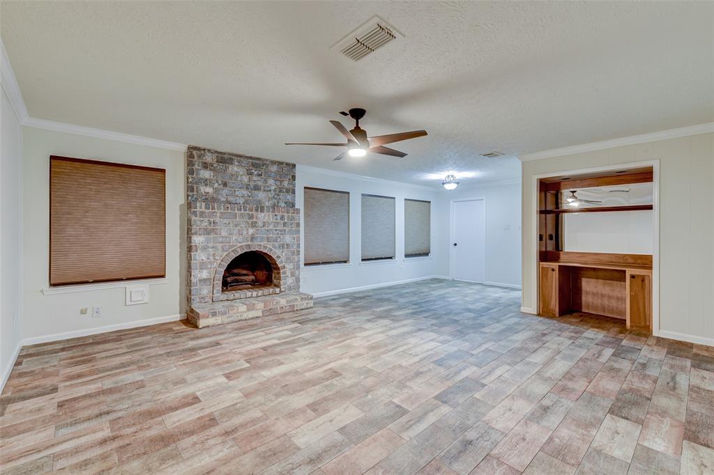 a view of a livingroom with a fireplace a ceiling fan and a window