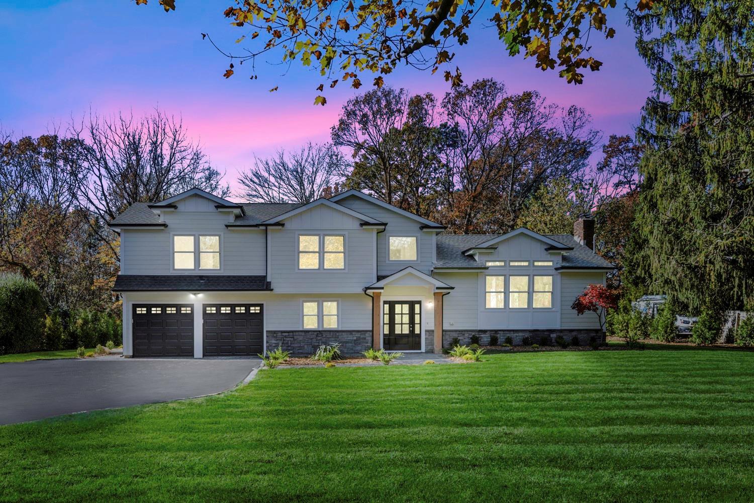 View of front facade featuring a lawn, a garage, and french doors