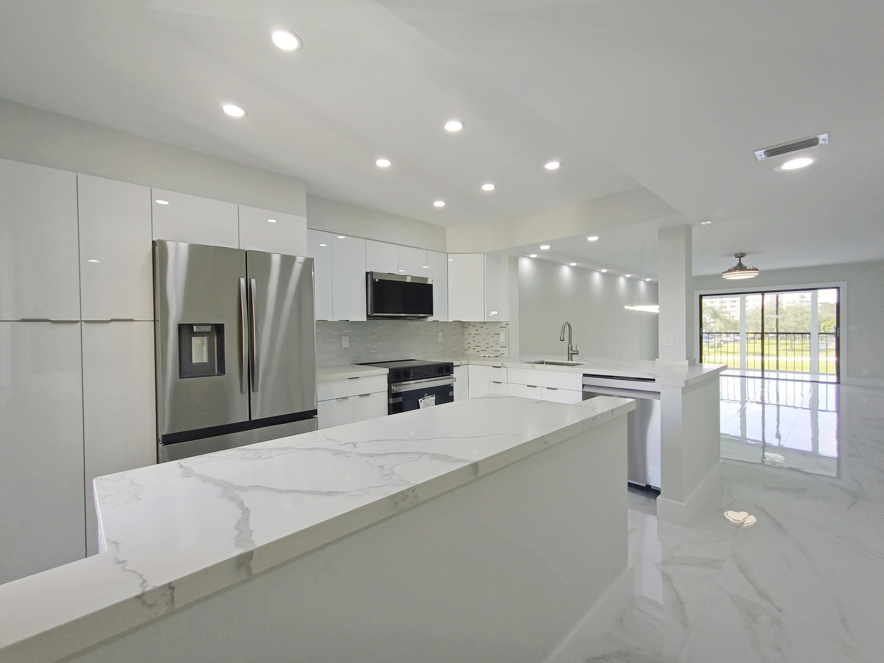 a large white kitchen with a large window and stainless steel appliances