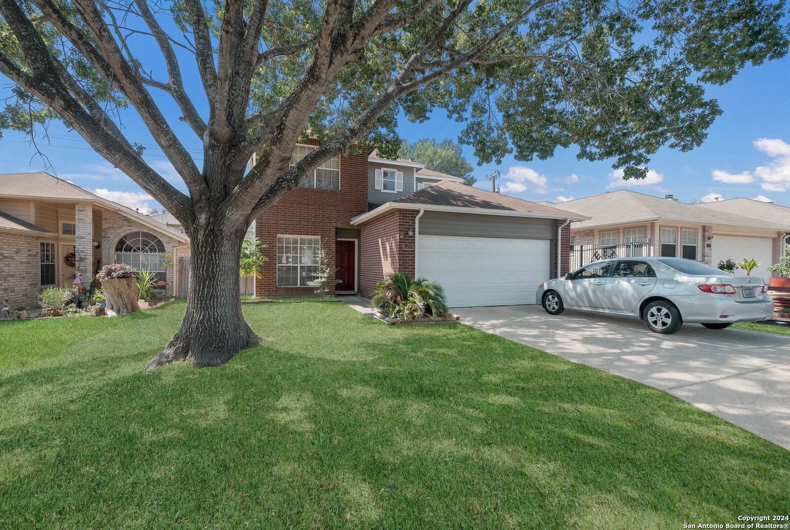 a front view of a house with a garden and trees