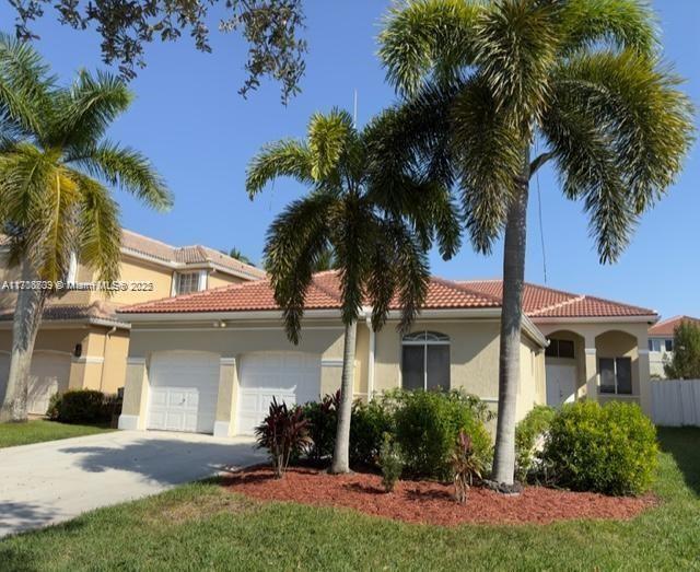 a front view of a house with a yard and palm trees