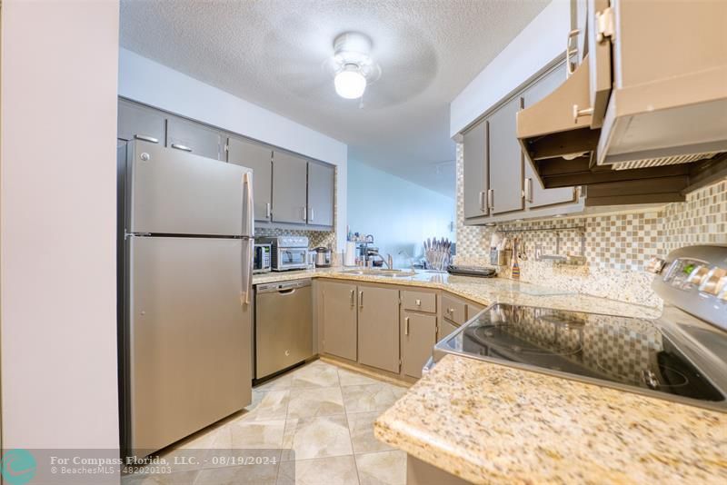 a kitchen with granite countertop a sink stainless steel appliances and cabinets