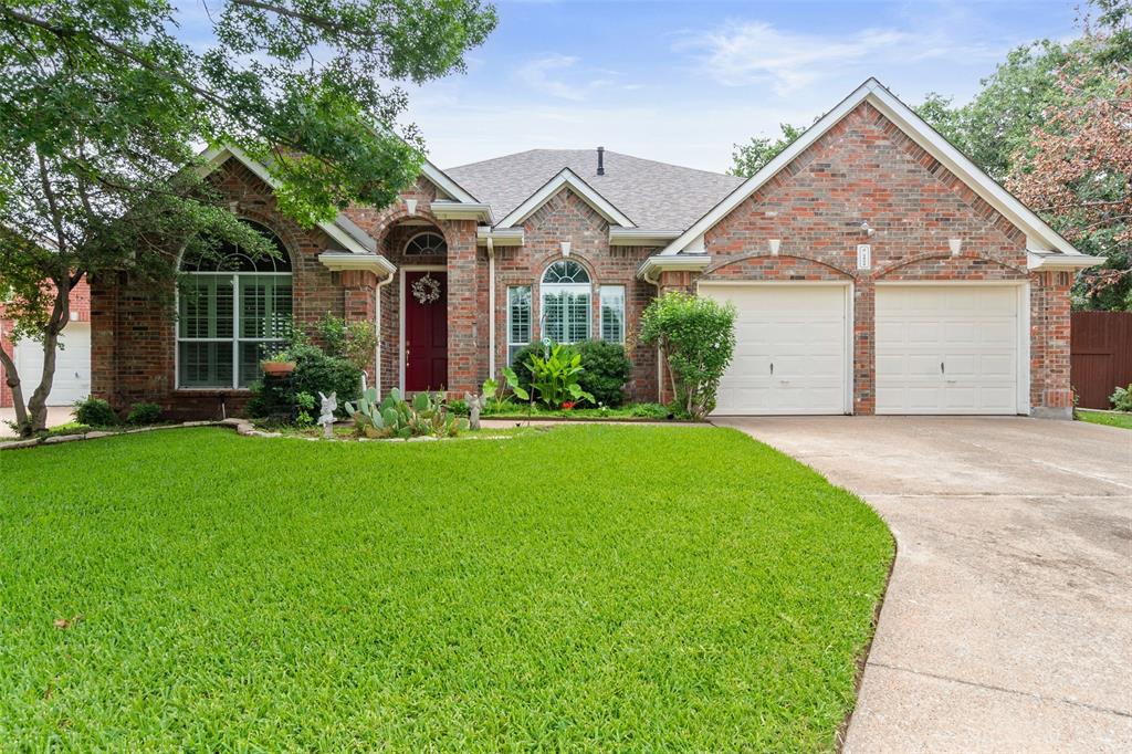 a view of a big yard in front of a house with plants and large tree