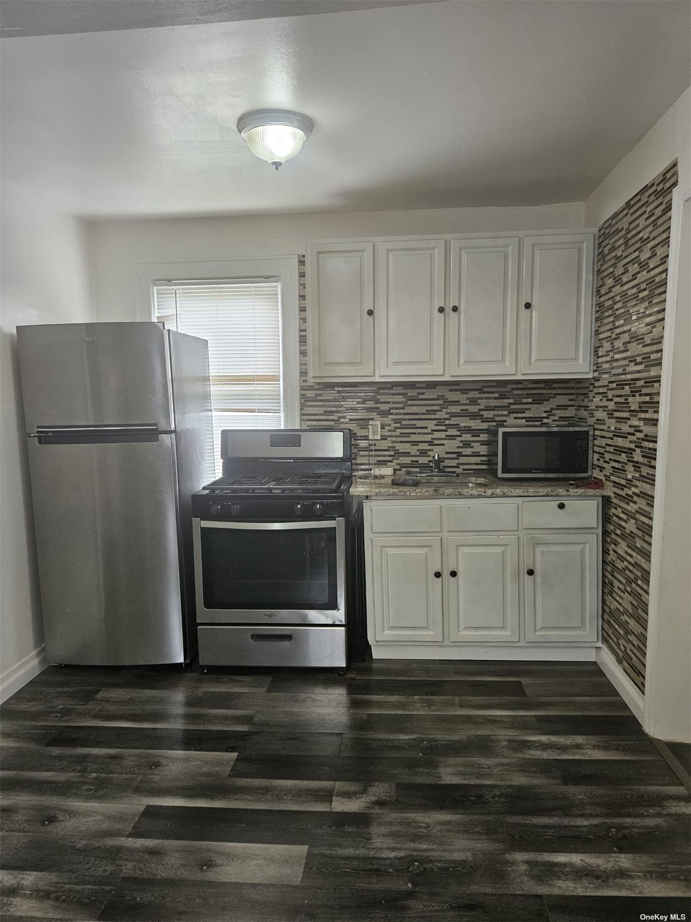 a kitchen with granite countertop white cabinets and stainless steel appliances