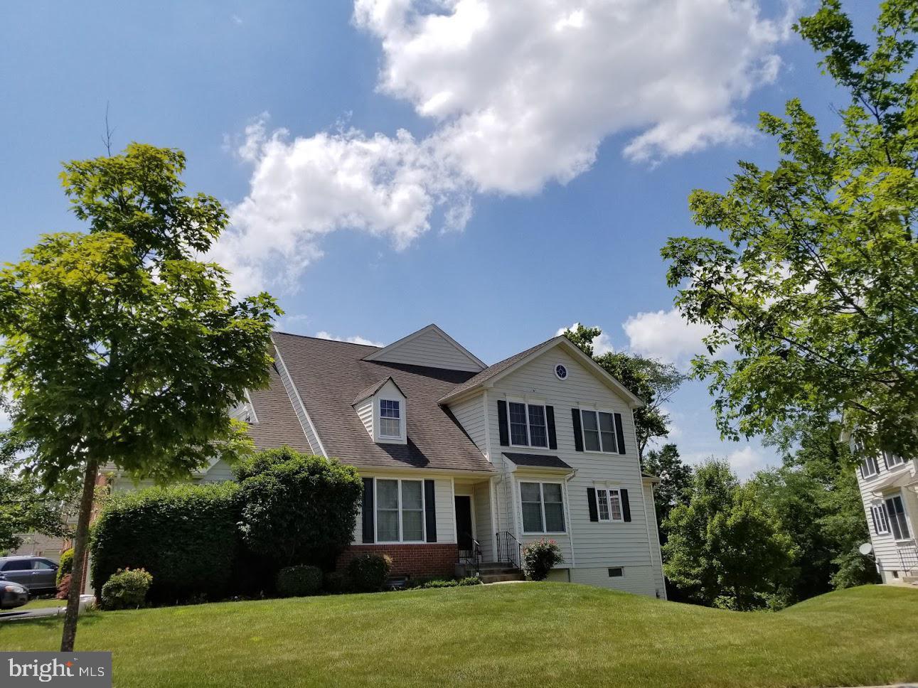 a view of a white house next to a yard with big trees