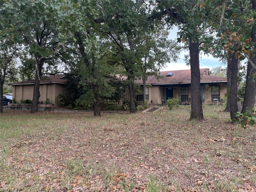 a view of a house with a yard and large tree