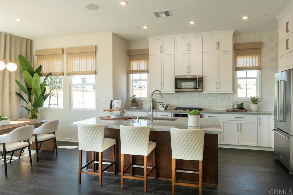 a kitchen with kitchen island granite countertop a table chairs sink and cabinets