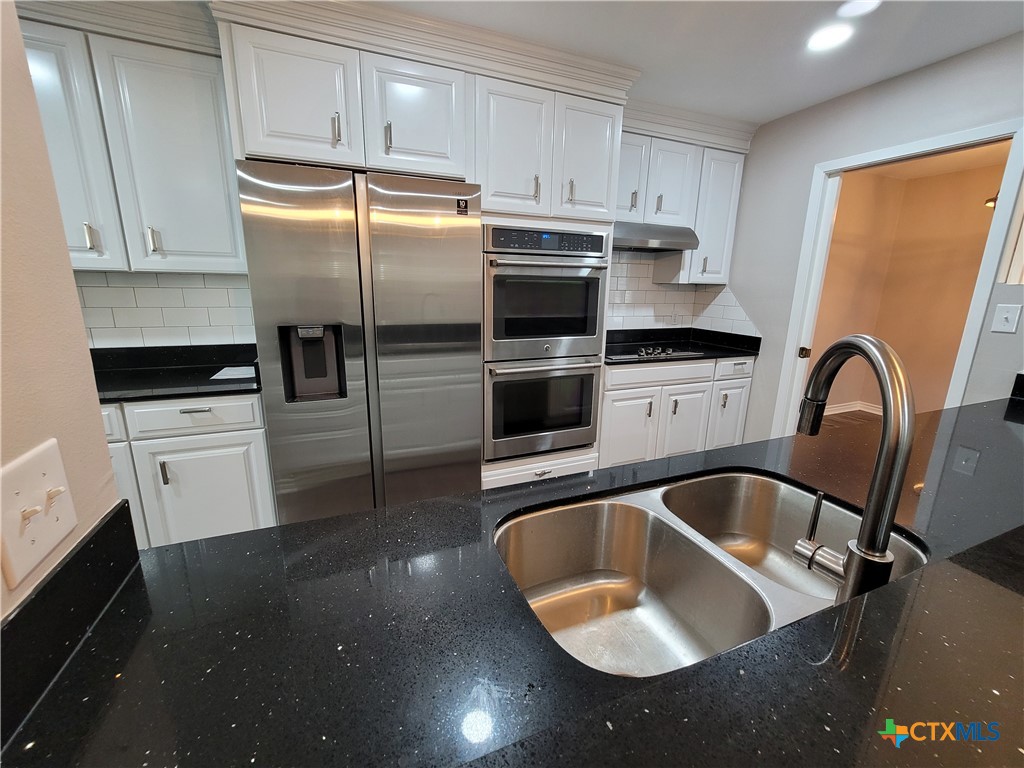 a kitchen with stainless steel appliances granite countertop a sink a stove and refrigerator