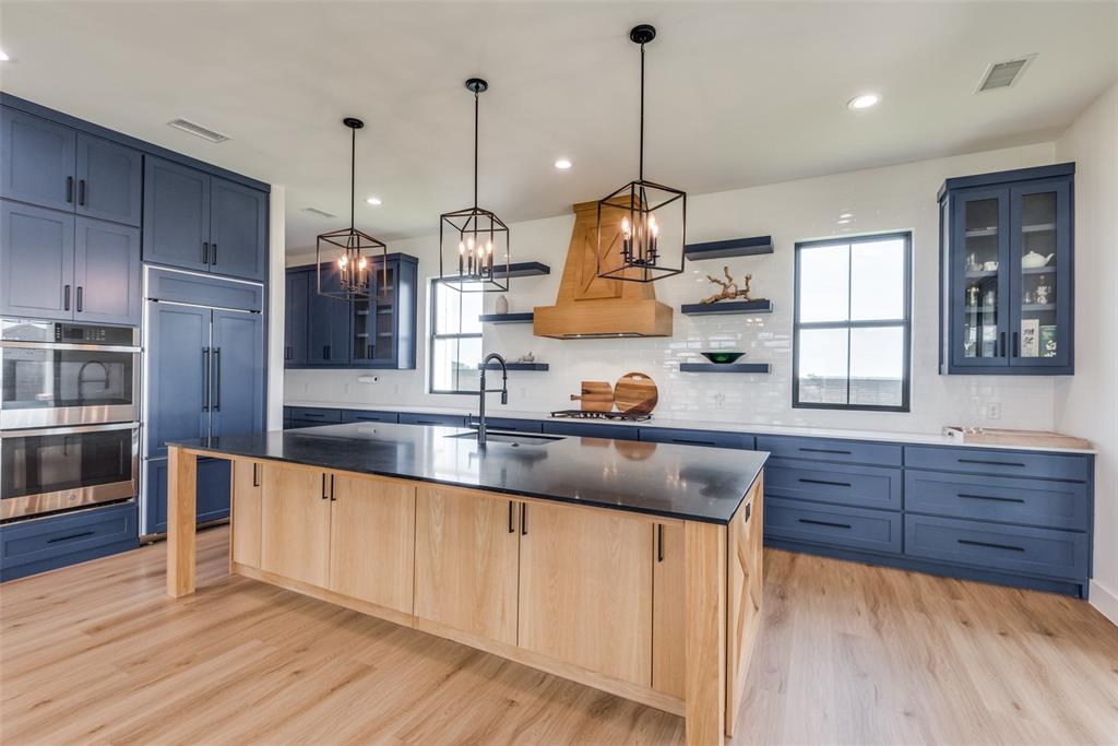 a kitchen with stainless steel appliances granite countertop a sink a stove and a wooden floor