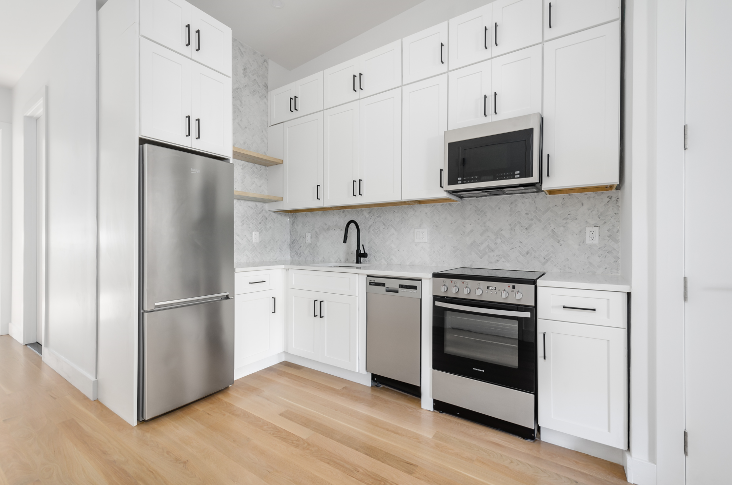 a kitchen with stainless steel appliances white cabinets white stove a microwave and a refrigerator