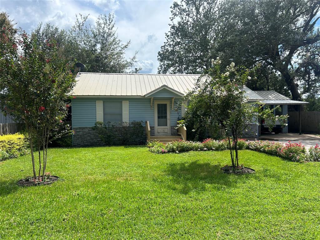 a view of a house with a yard and a large tree