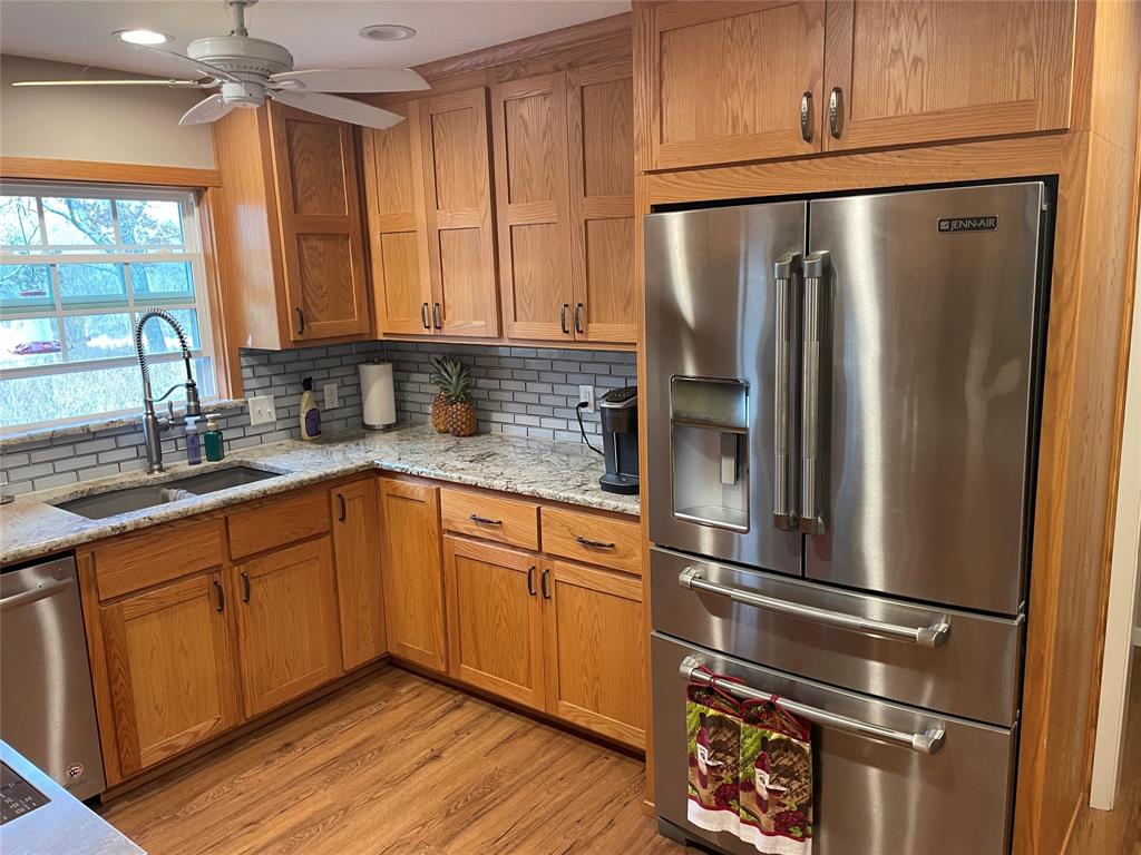 a kitchen with stainless steel appliances granite countertop a refrigerator a sink and wooden cabinets