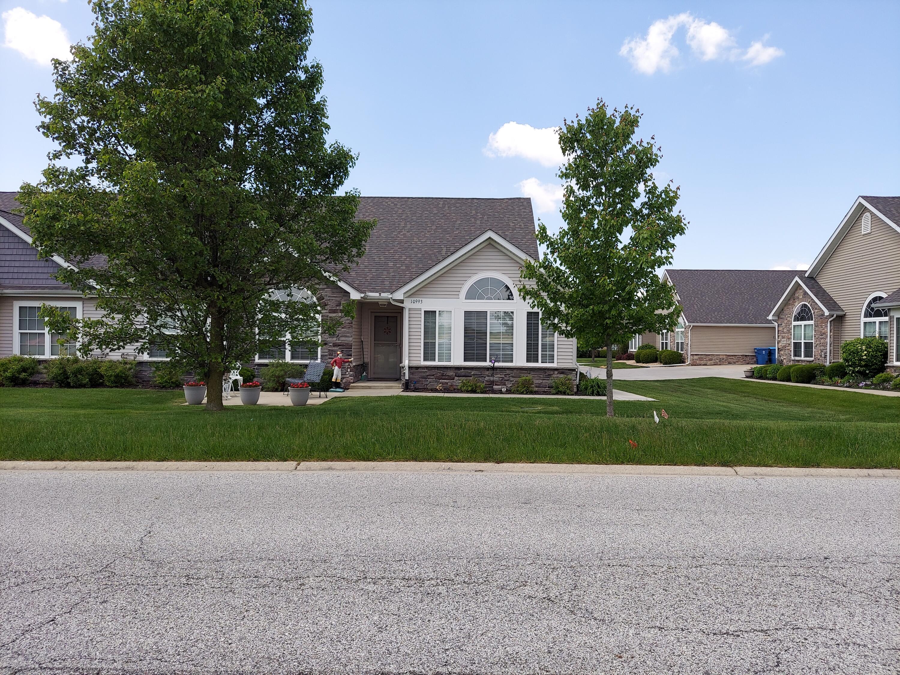 a front view of a house with a yard and large trees