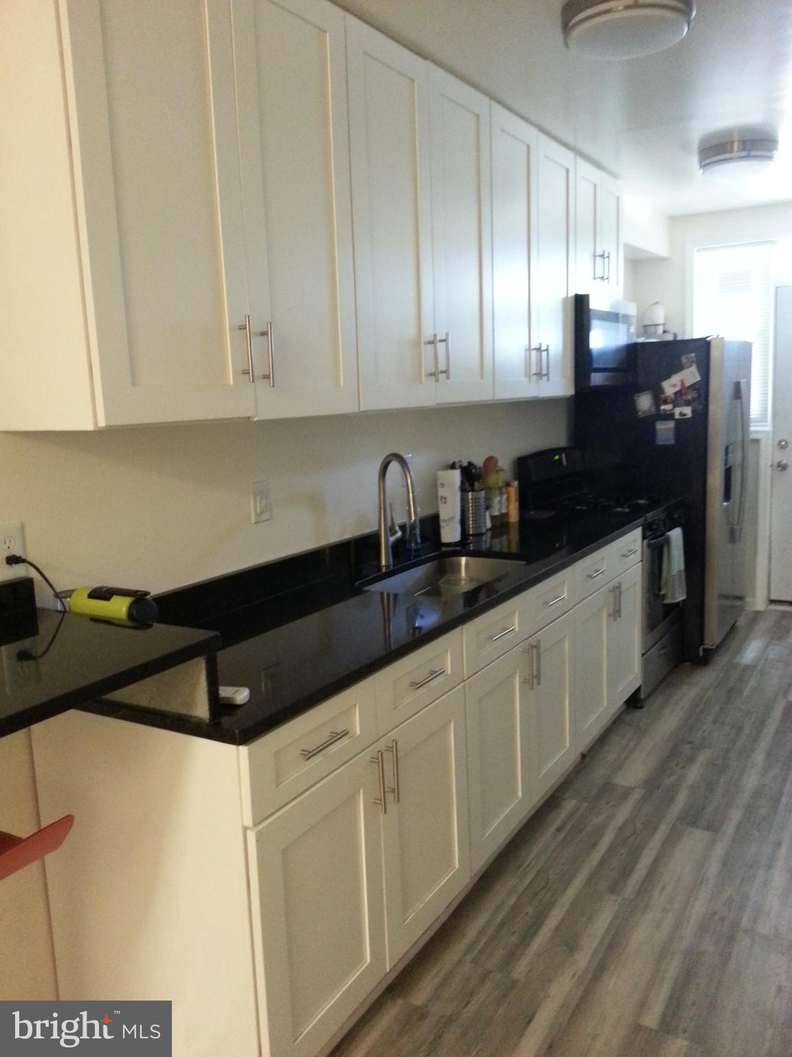 a kitchen with granite countertop white cabinets and black appliances