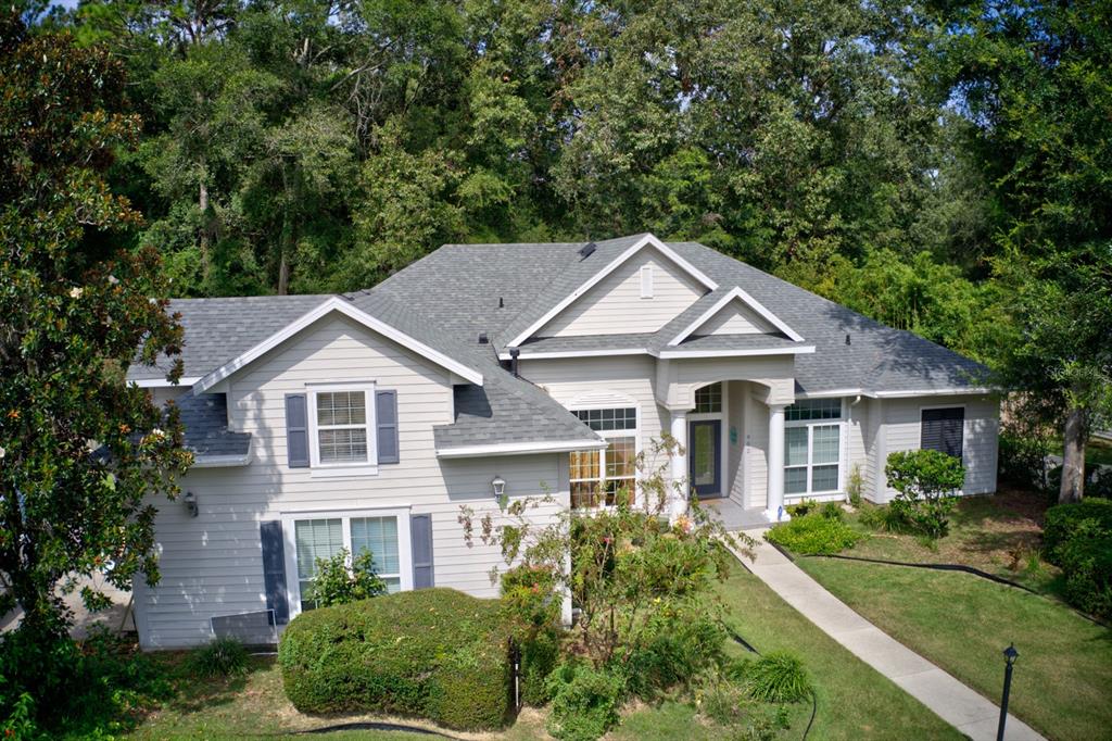 a view of a white house next to a yard with large trees