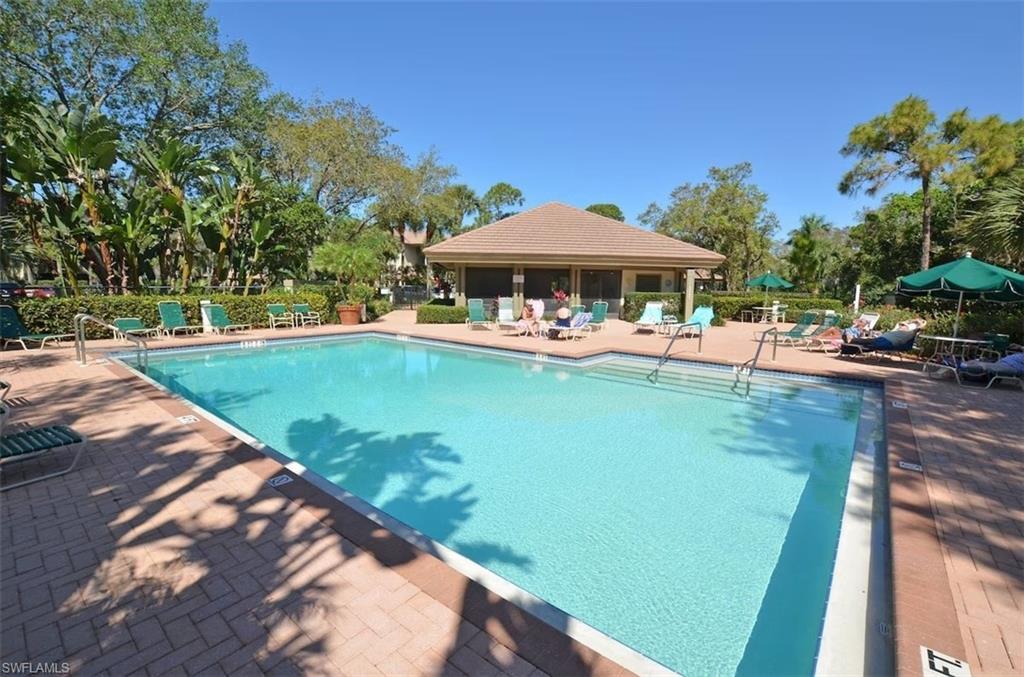 a view of a swimming pool with a table and chairs under an umbrella