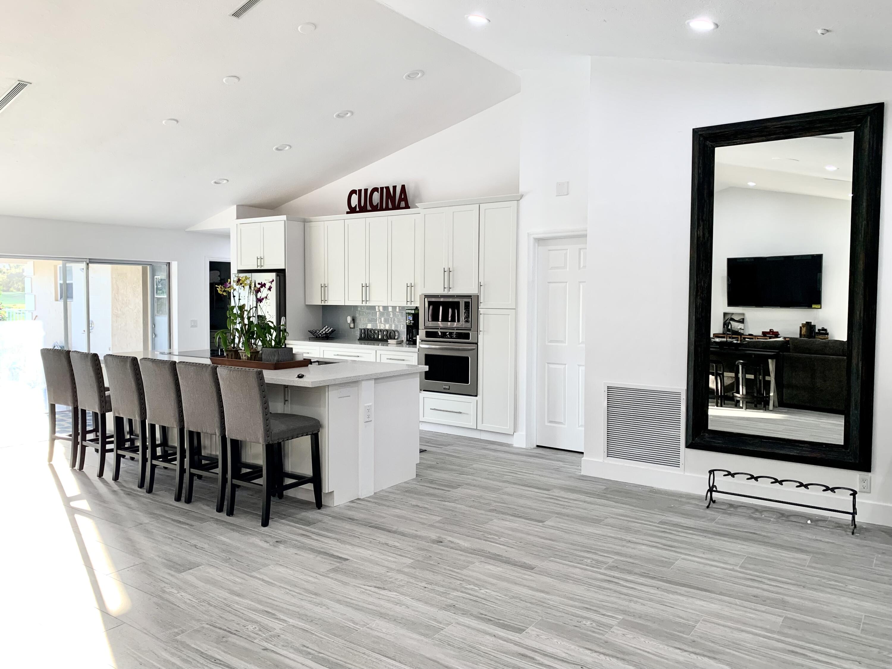 a large white kitchen with stainless steel appliances granite countertop a stove and a wooden floors