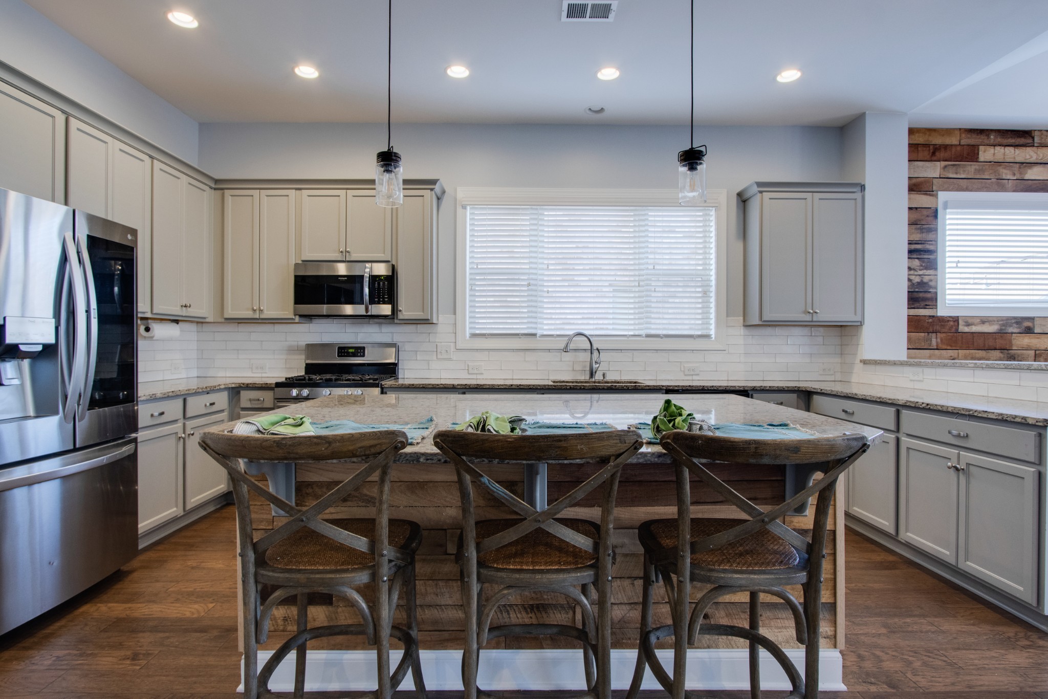 a kitchen with kitchen island granite countertop a table chairs microwave and refrigerator