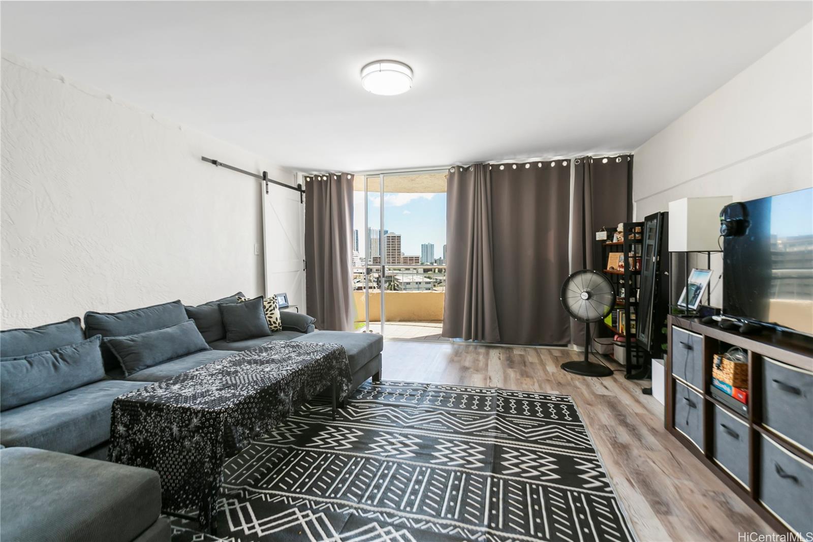 a living room with furniture a flat screen tv and a window