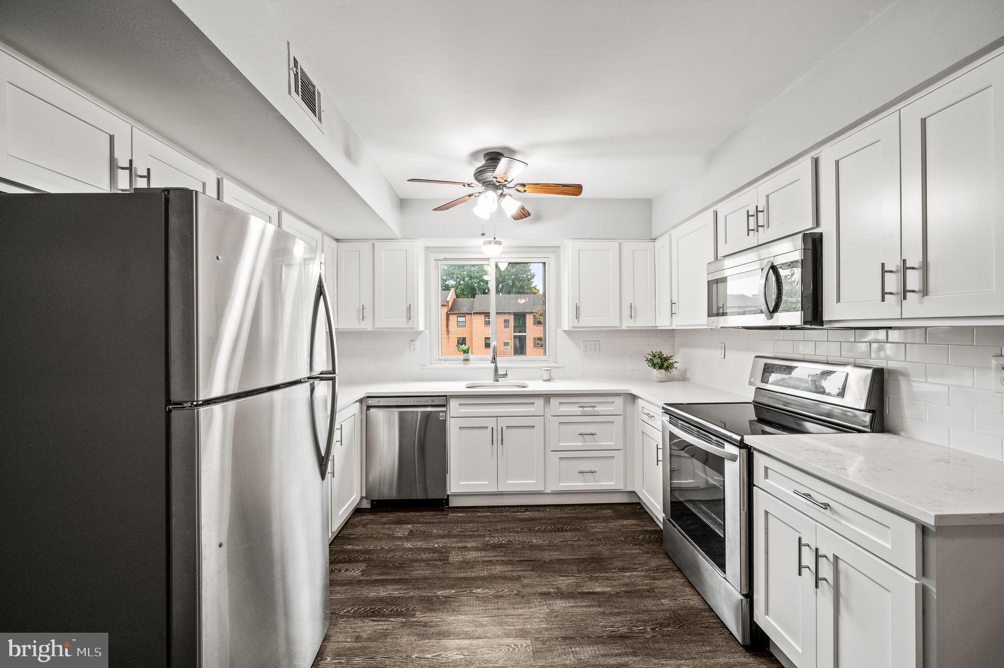 a kitchen with white cabinets stainless steel appliances and a window