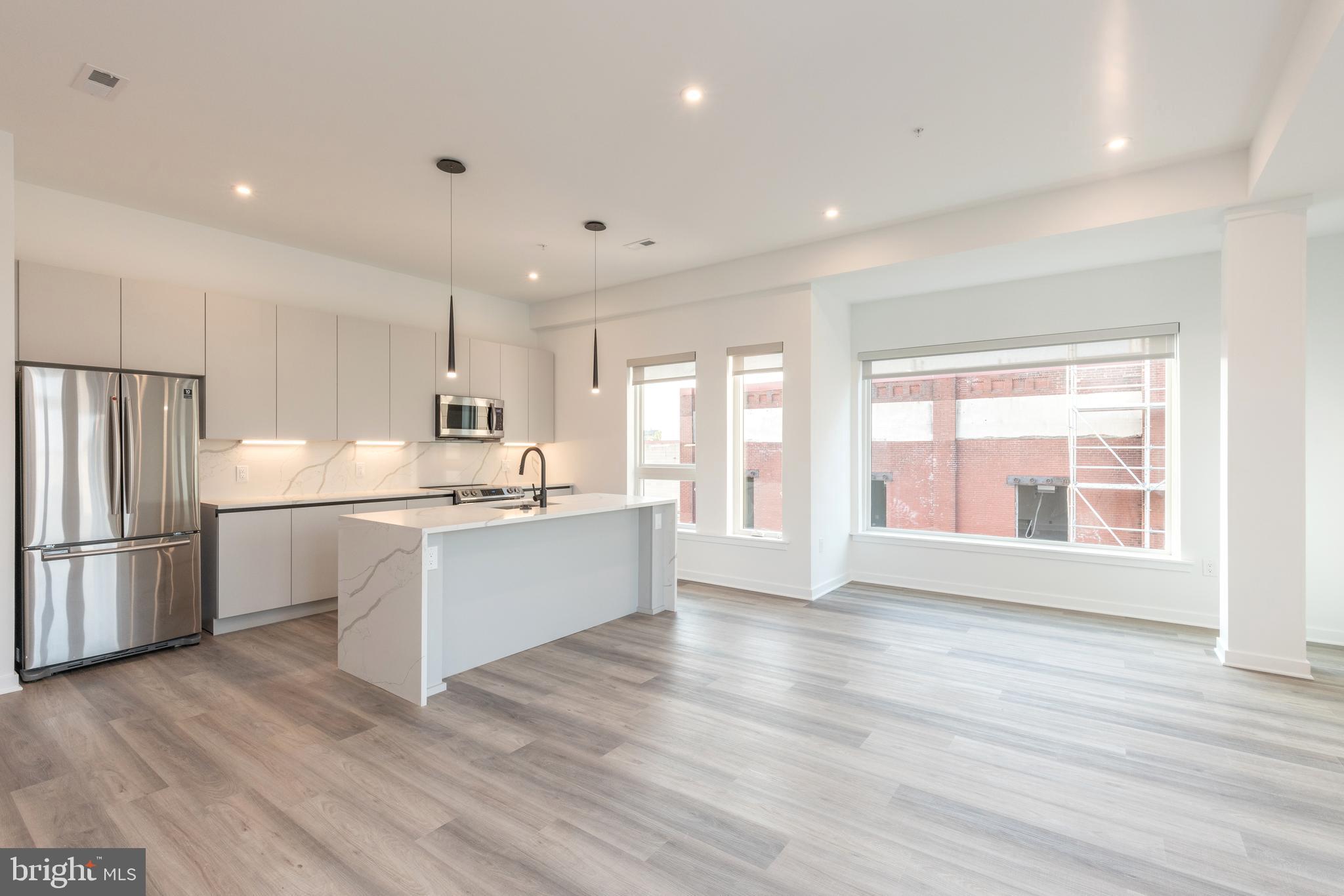 a large white kitchen with wooden floors and white stainless steel appliances