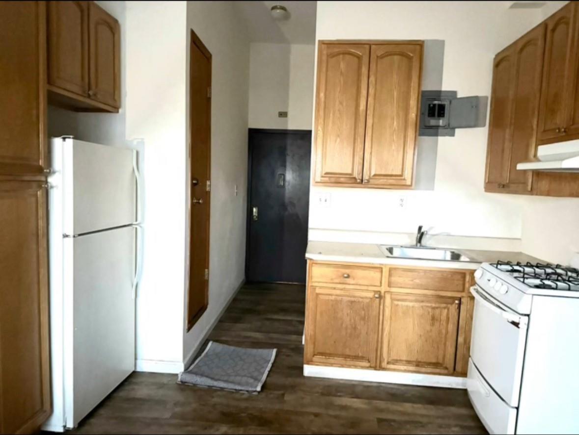 Kitchen featuring sink, dark hardwood / wood-style floors, and white appliances