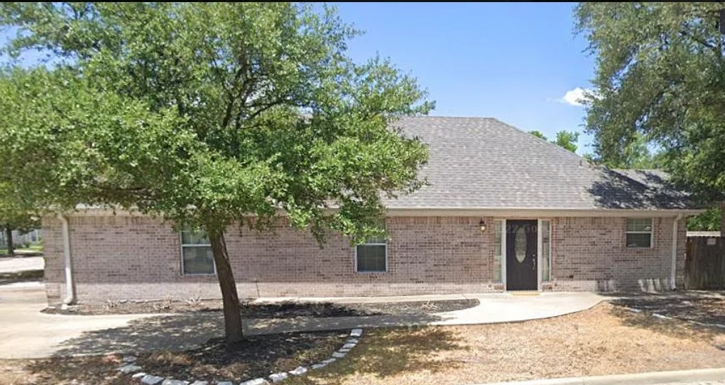 a front view of a house with a tree