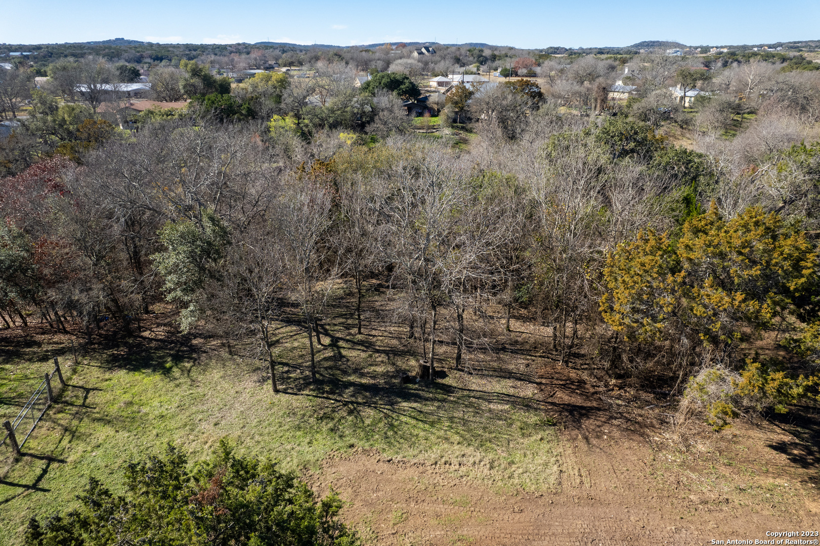 a view of a dry yard with trees in the background