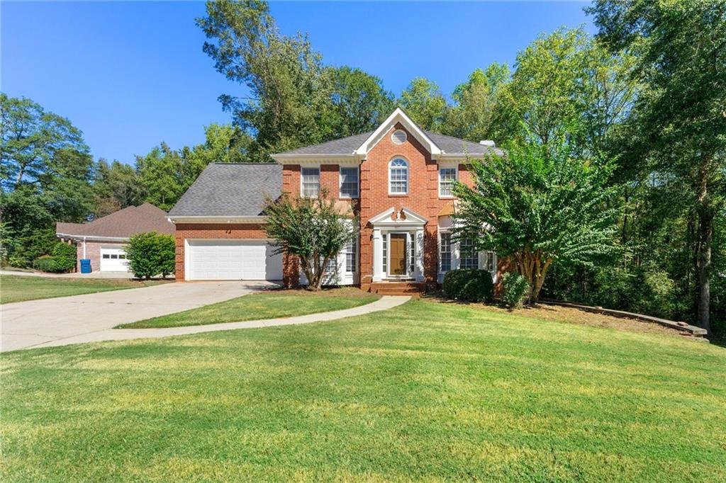 a front view of a house with a yard and trees