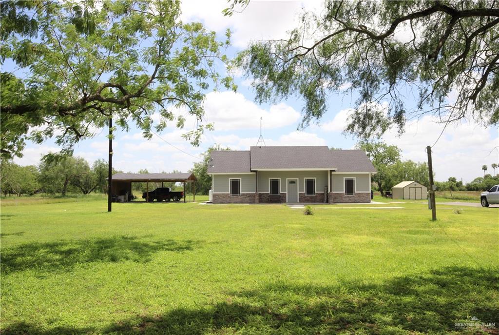 a view of an house with backyard and a tree