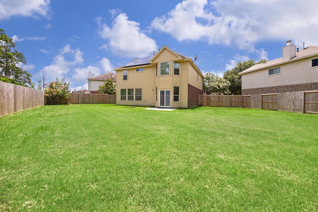 a view of a house with a yard and a large tree