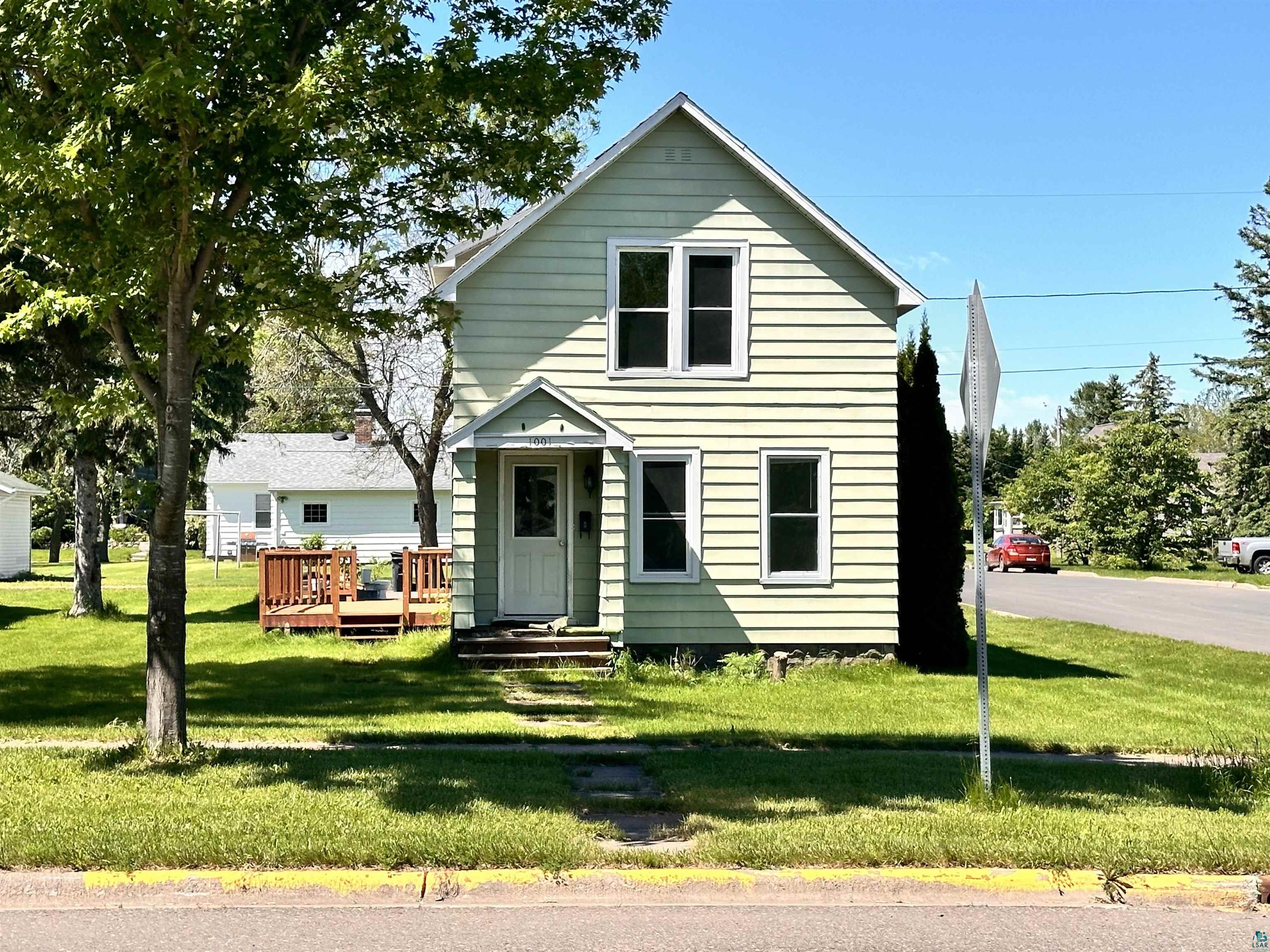 View of front of house featuring a front lawn and a deck