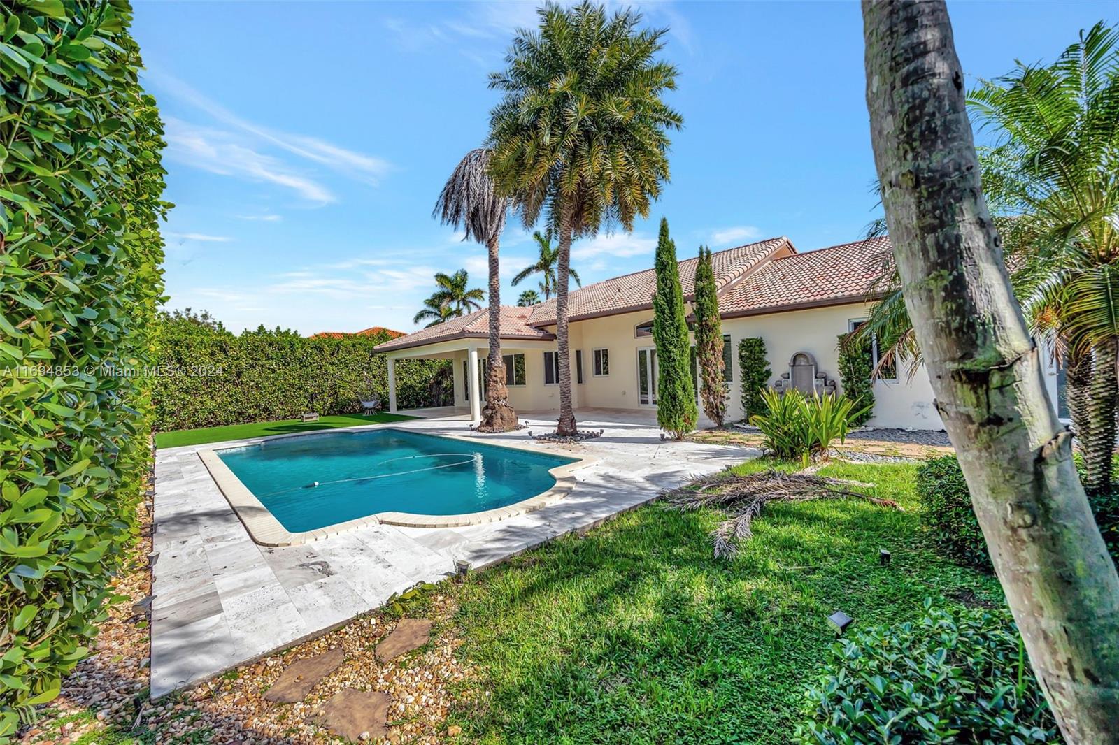 a view of a house with a yard and palm trees