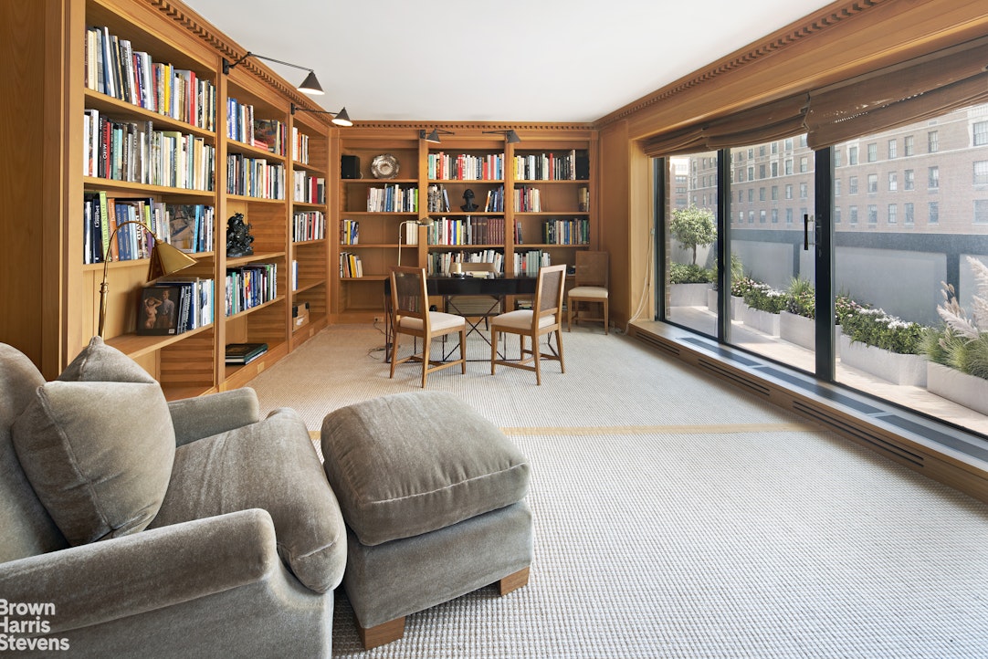 a living room with furniture a bookshelf and a large window